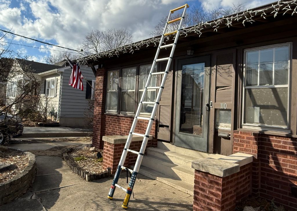 Werner TS1250 telescoping ladder, fully extended at 12.5 feet reaches from the driveway to past the roof or a brown ranch home that still has Christmas icicle lights on it.